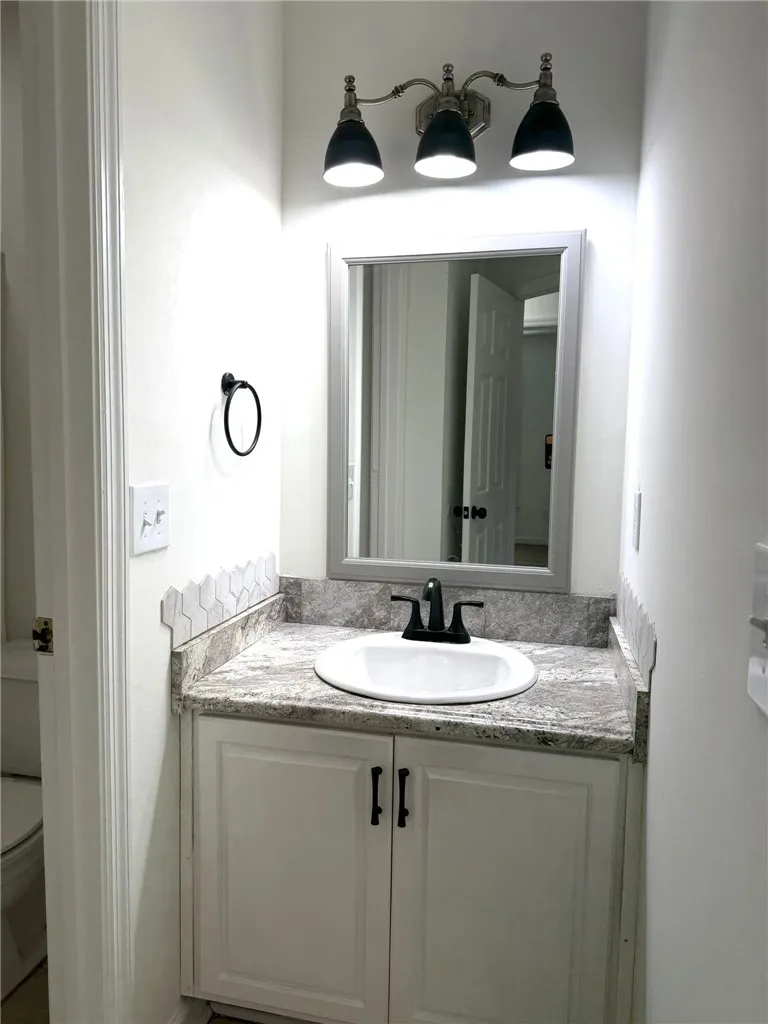 A well-appointed bathroom vanity offers a practical sink set into granite countertops.