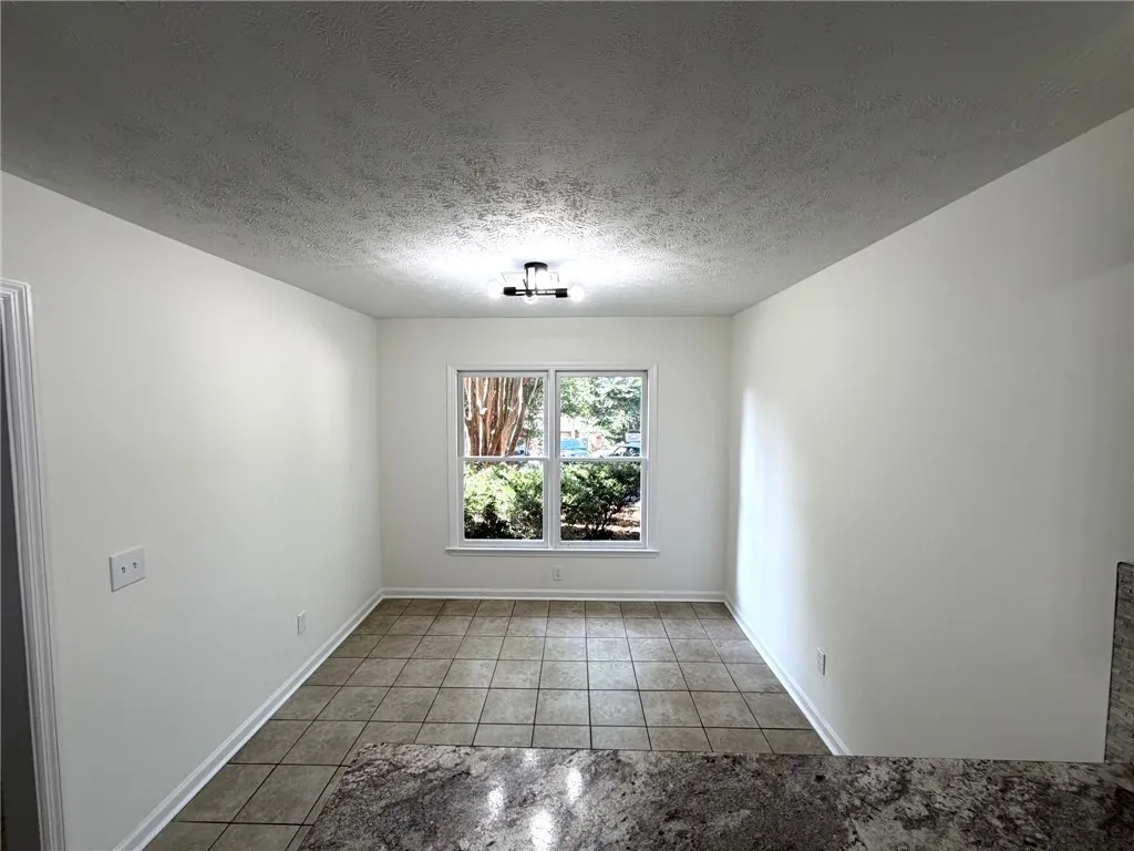 A well-lit breakfast area featuring durable tile flooring and views of the outdoors.