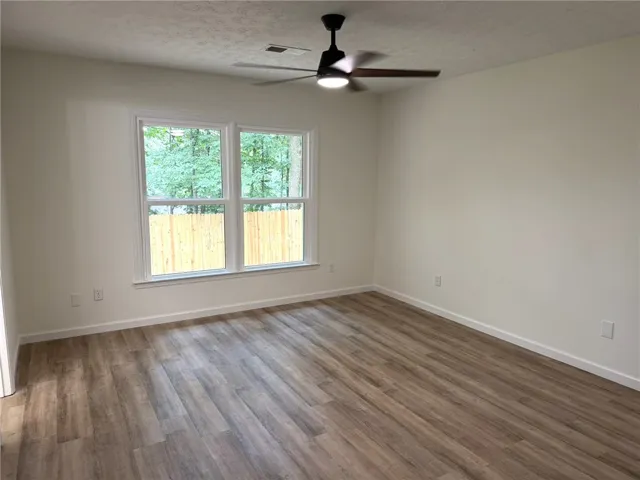 Natural light floods this room, highlighting the warm wood-tone flooring and contemporary ceiling fan.