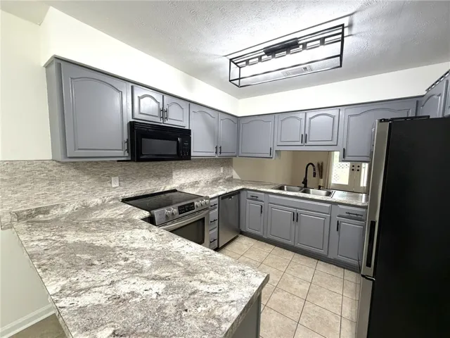 Updated kitchen featuring elegant grey cabinetry and new appliances.