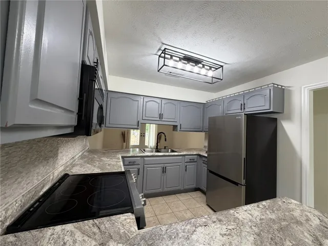 Modern kitchen with gray cabinetry, durable countertops, and sleek stainless steel appliances.