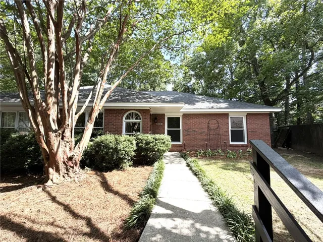 A classic brick exterior welcomes with mature trees and a manicured walkway.