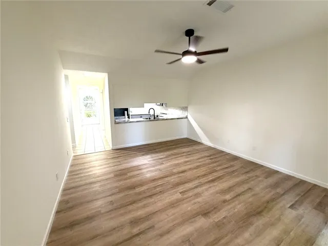 Laminate flooring extends through this welcoming space, anchored by a modern ceiling fan.