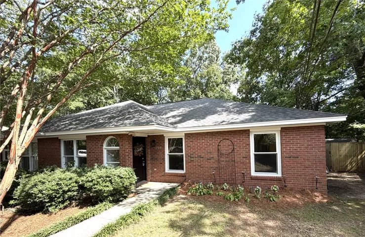 A well-kept brick residence presents a welcoming facade with a concrete pathway leading to the entrance.