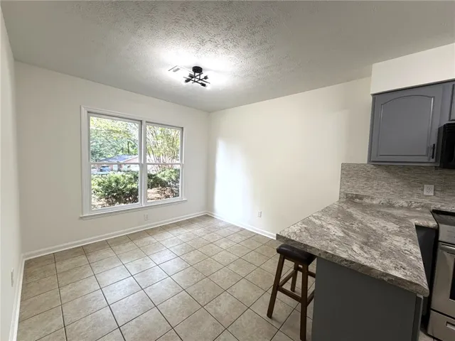 A well-lit kitchen area features durable tile flooring and ample natural light from a large window.