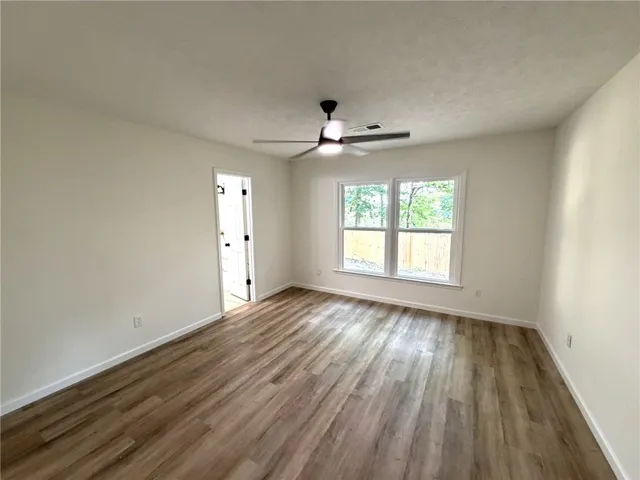Ample windows invite natural light into this versatile room with durable flooring and modern ceiling fan.