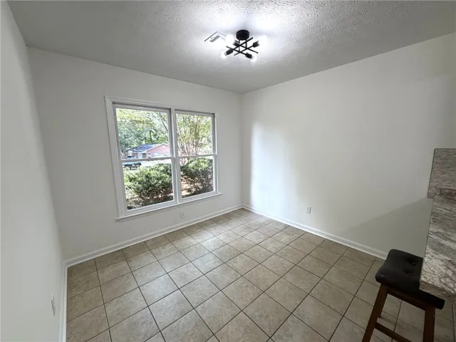 Bright breakfast area with large windows and durable tile flooring.