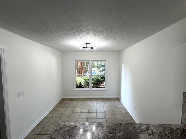 A well-lit breakfast area featuring durable tile flooring and views of the outdoors.