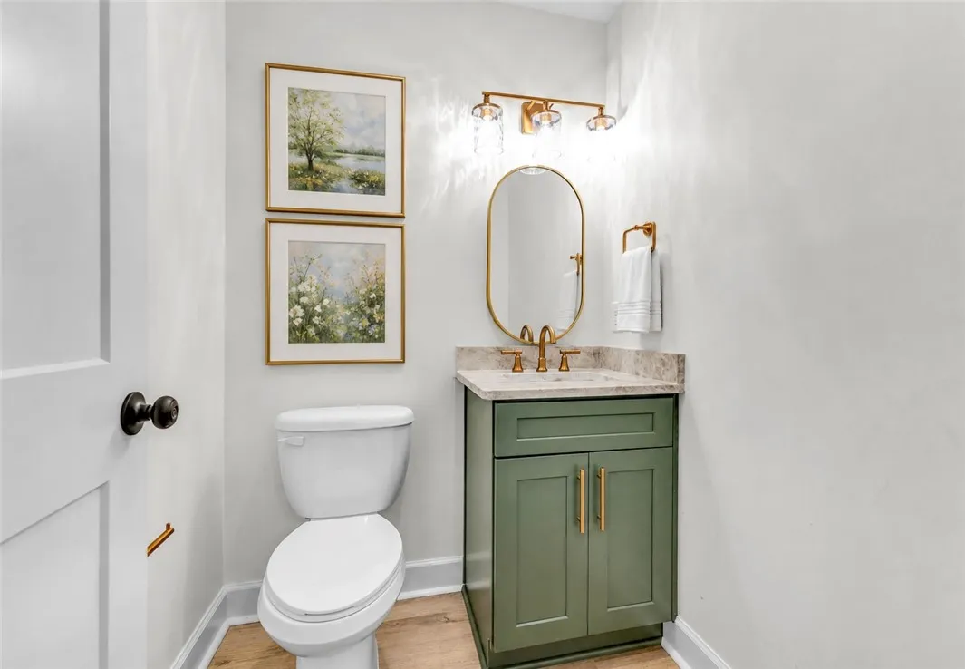 A chic half-bath featuring a stylish vanity and light wood flooring.