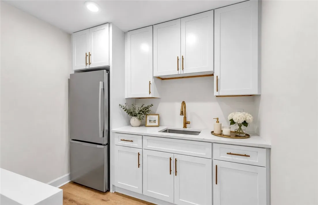 A sleek kitchenette with white cabinetry and a convenient stainless steel refrigerator.