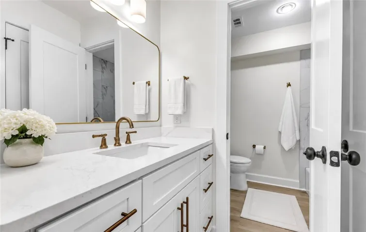 A well-lit primary bathroom features a double vanity with stone counters and a spacious mirror.