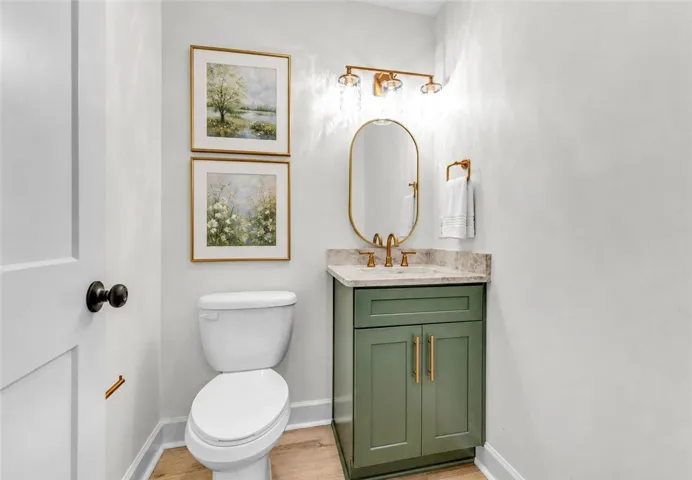 A chic half-bath featuring a stylish vanity and light wood flooring.