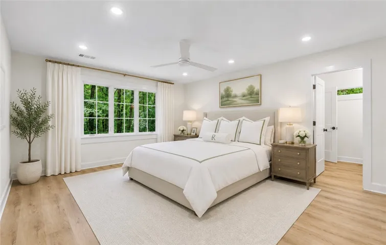 A spacious primary bedroom with a large window and light-toned flooring.