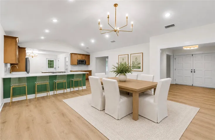 A striking green kitchen island anchors this inviting open-concept dining area with warm wood flooring.