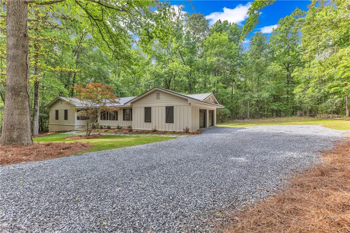 A tranquil woodland setting surrounds this charming home with a spacious gravel driveway.