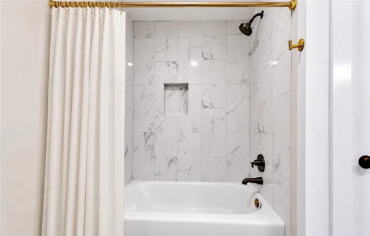 Marble-tiled shower surround with a sleek black showerhead and an integrated niche.
