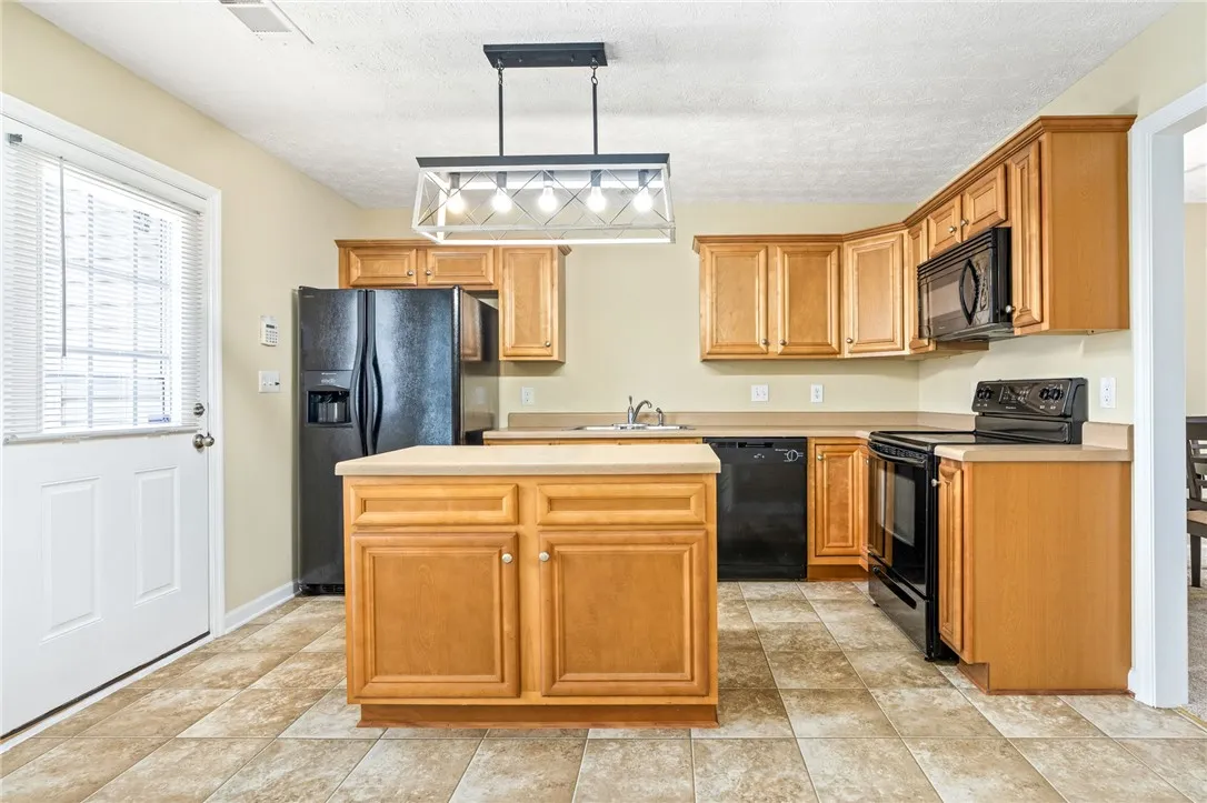 An inviting kitchen showcasing a central island and a full complement of black appliances.