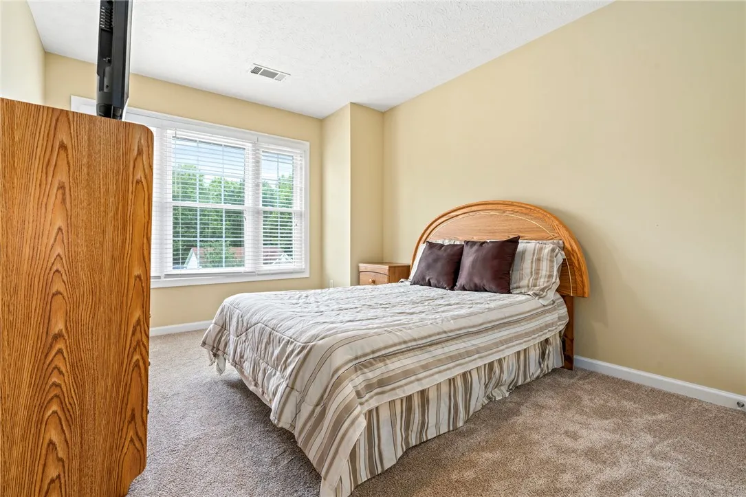 Well-lit sleeping quarters with plush carpet and a wide window offering verdant outdoor views.