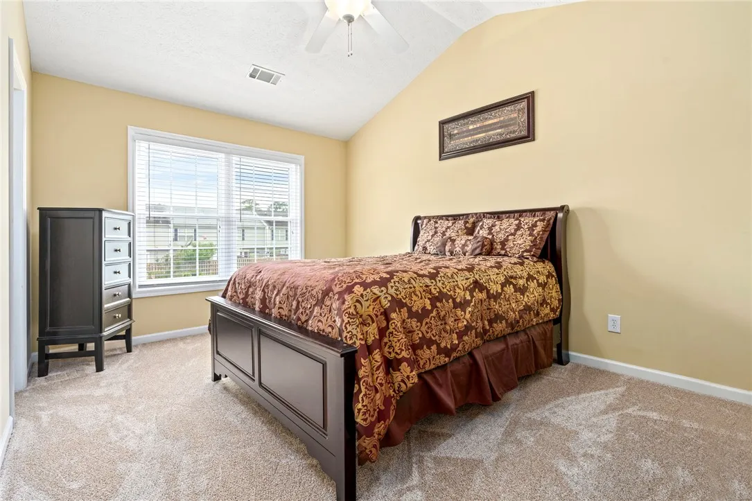 A comfortable bedroom features plush carpeting and a sun-filled window, perfect for relaxation.