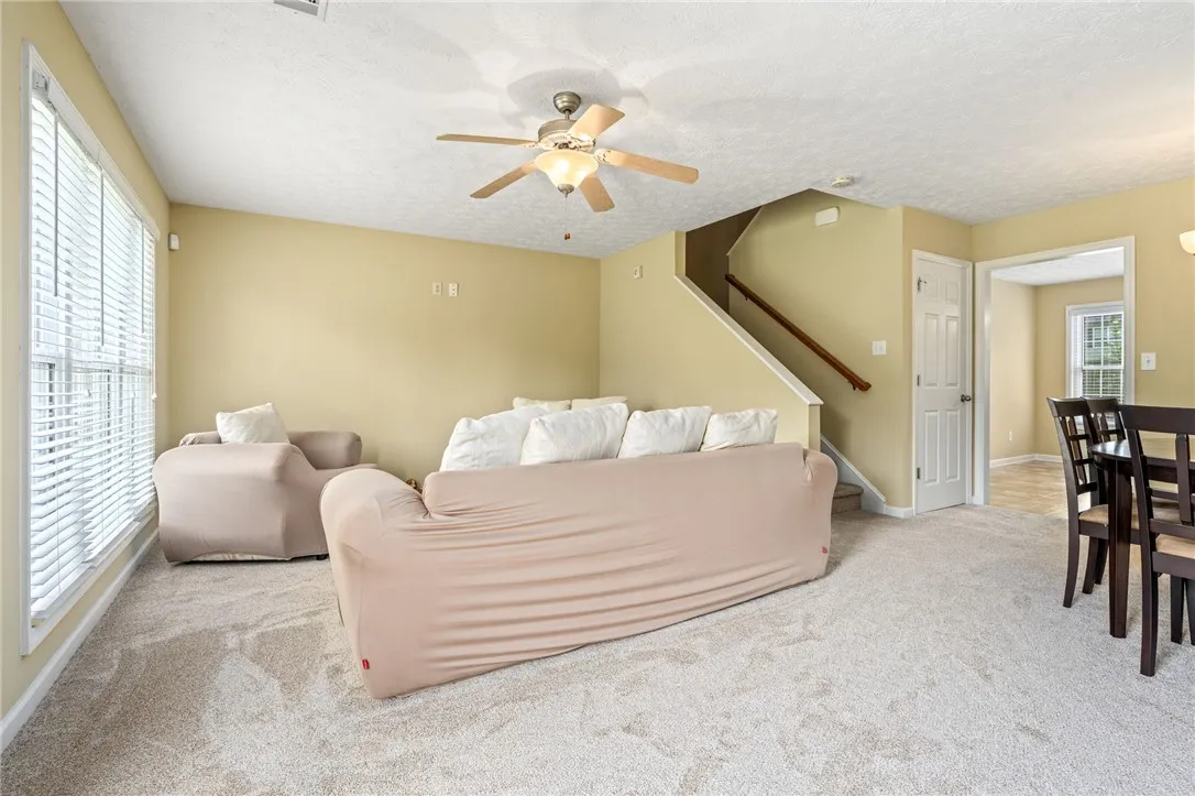 A versatile living area features plush carpeting and a convenient staircase leading to the upper level.