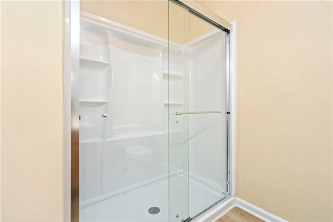 A well-maintained, walk-in shower with built-in shelving offers a refreshing bathing experience.