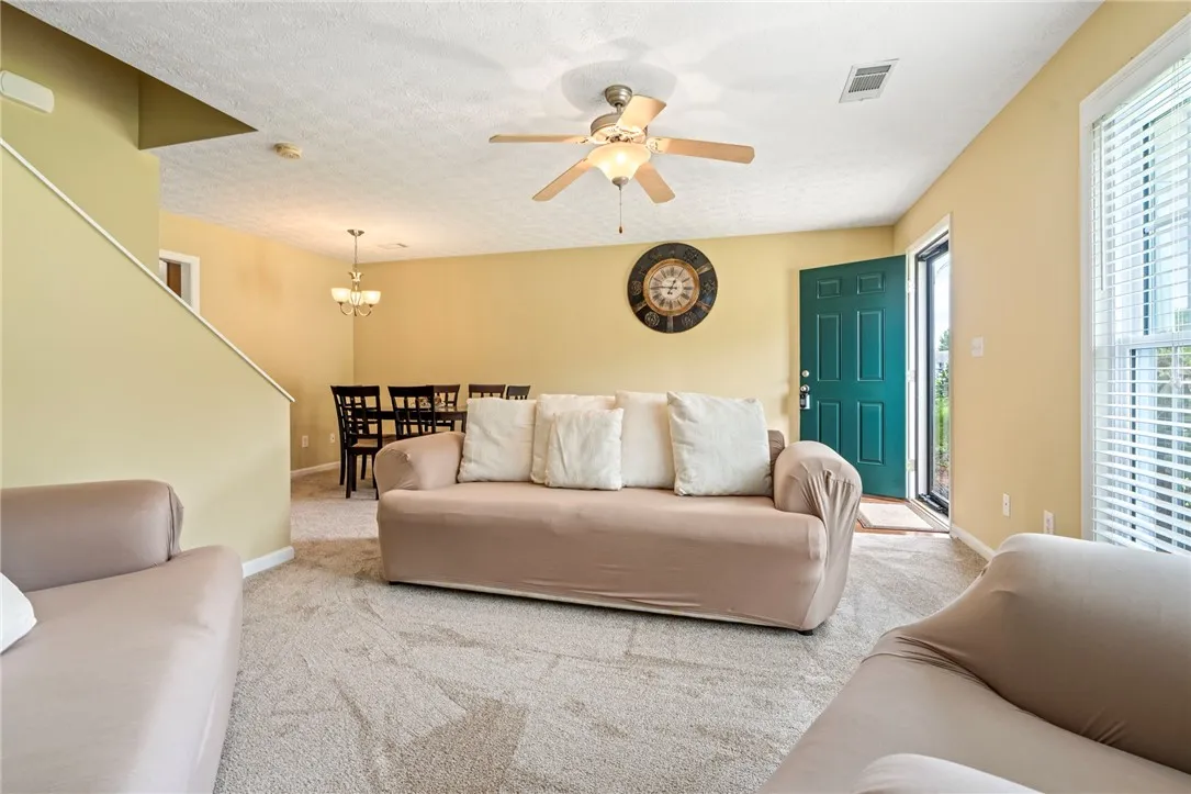 A welcoming interior reveals an open-concept living and dining area with soft carpeting and natural light.