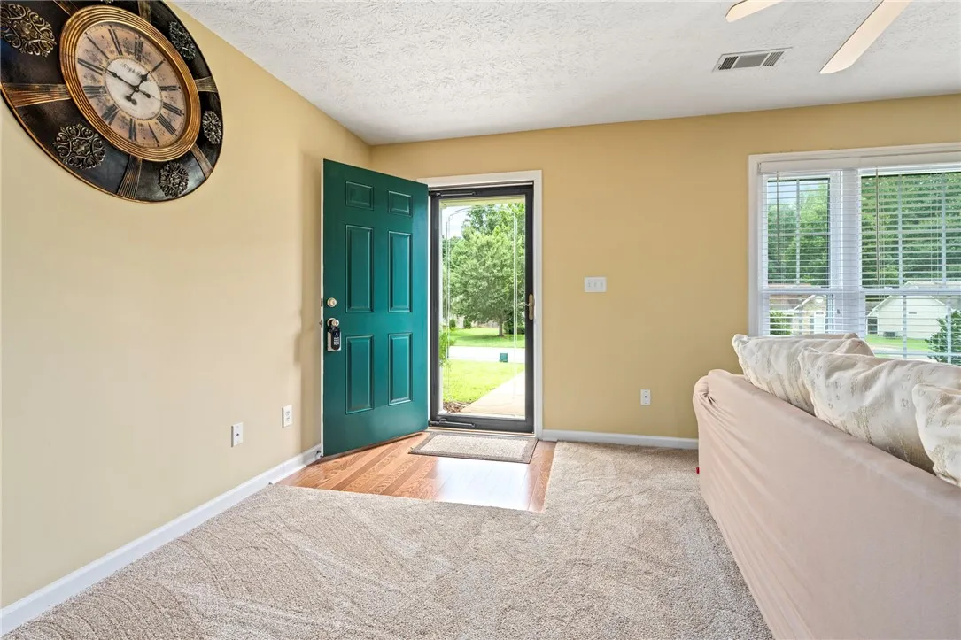 A welcoming entry area with a teal door opens to rich wood and soft carpeting.