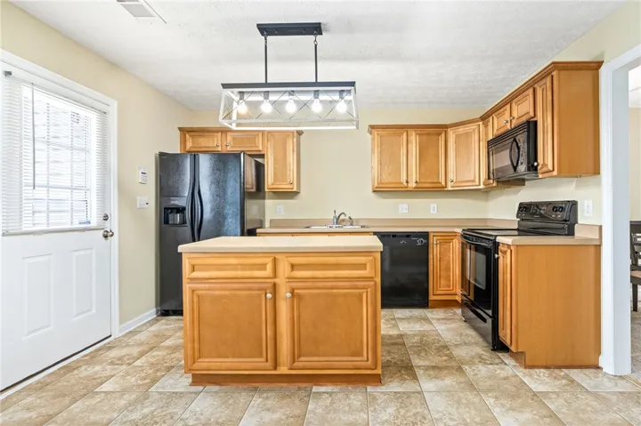 An inviting kitchen showcasing a central island and a full complement of black appliances.