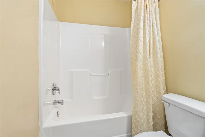 A pristine white tub and shower combination with modern fixtures awaits in this well-appointed bathroom.