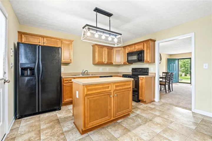 A well-appointed kitchen features a central island, rich wood cabinetry, and sleek black appliances.