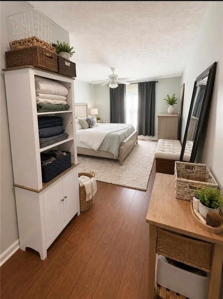 A well-lit bedroom features rich hardwood flooring and a cozy area rug, complemented by a prominent ceiling fan.