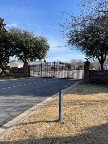 Secure community entrance with an elegant wrought iron gate and decorative brick pillars.
