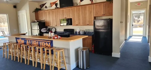 A vibrant community recreation area with a functional kitchen, full bar, and direct pool access.