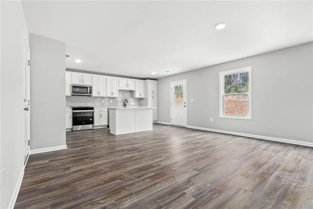 An open concept kitchen and living space, where durable plank flooring extends through a bright, inviting area.