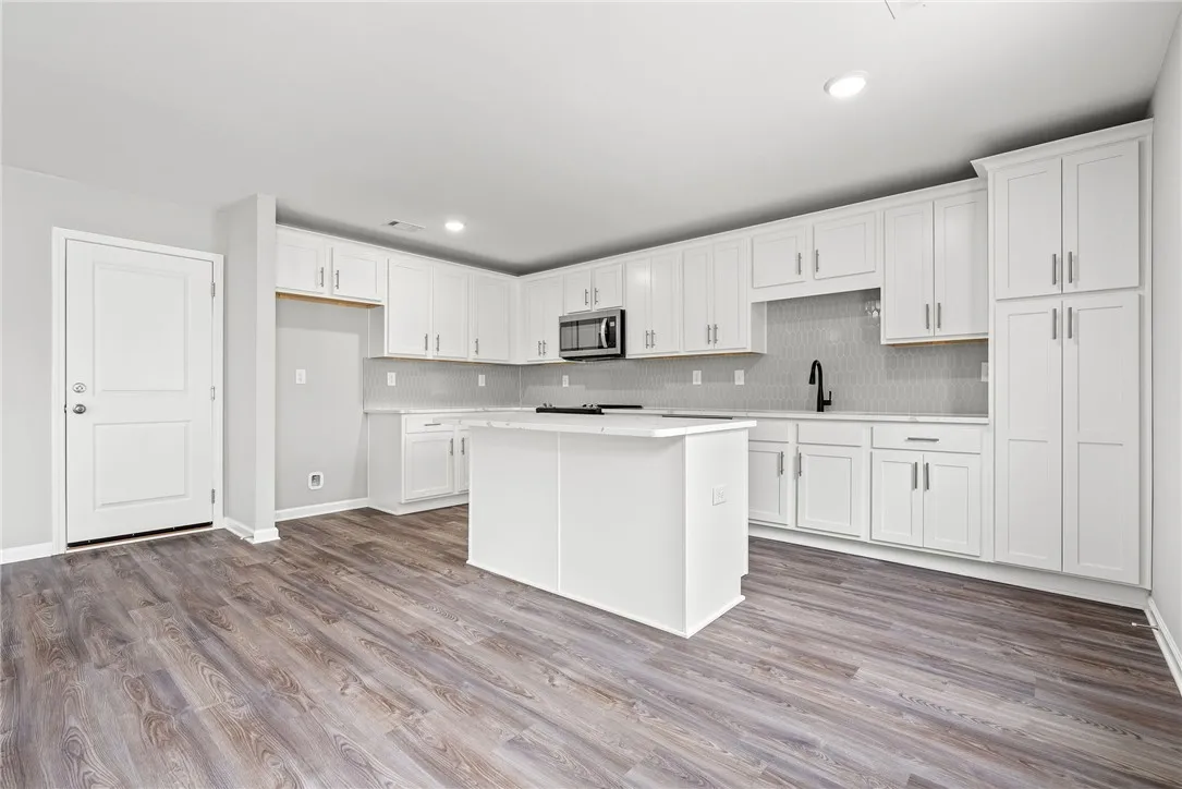 A well-appointed kitchen showcasing an island, plentiful white cabinetry, and durable flooring.