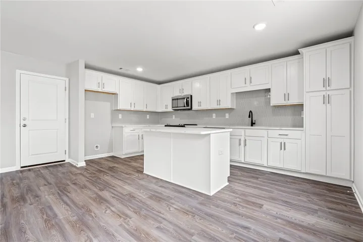 A well-appointed kitchen showcasing an island, plentiful white cabinetry, and durable flooring.