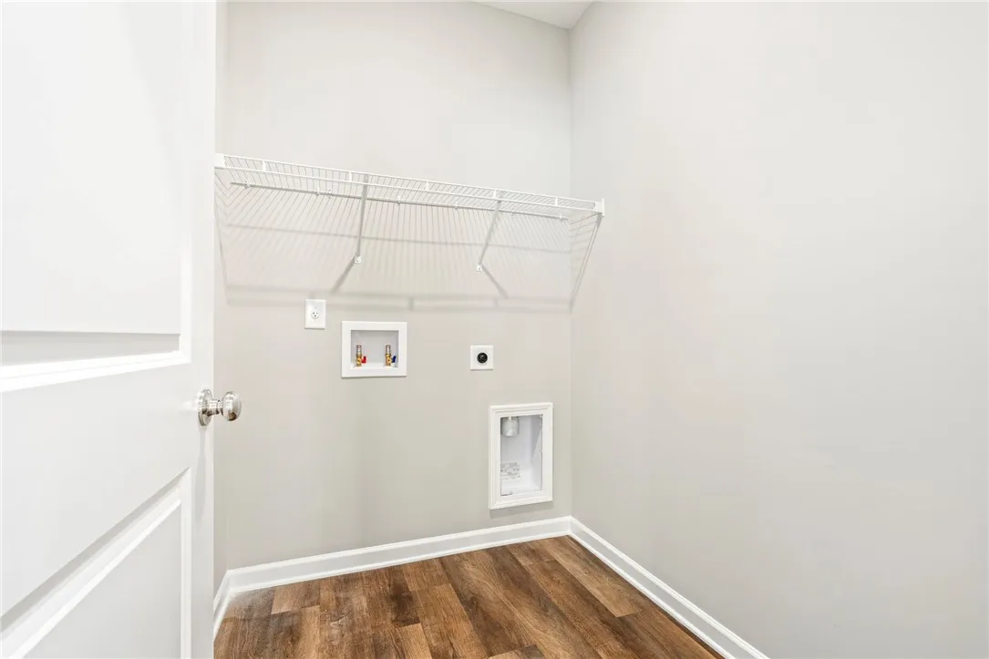 Rich wood-inspired flooring and utility hookups define this functional laundry space.