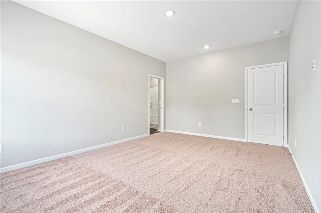 Soft carpeting pairs with neutral walls under recessed lighting in this comfortable secondary bedroom.