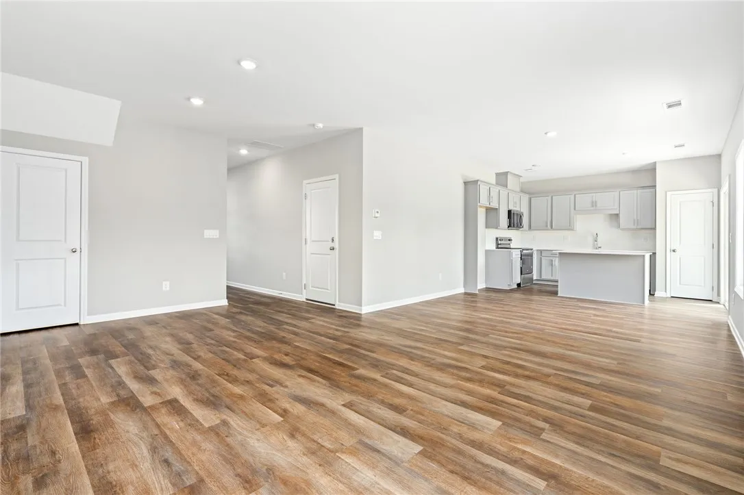 Rich wood-look flooring anchors a modern open layout flowing seamlessly into the kitchen.