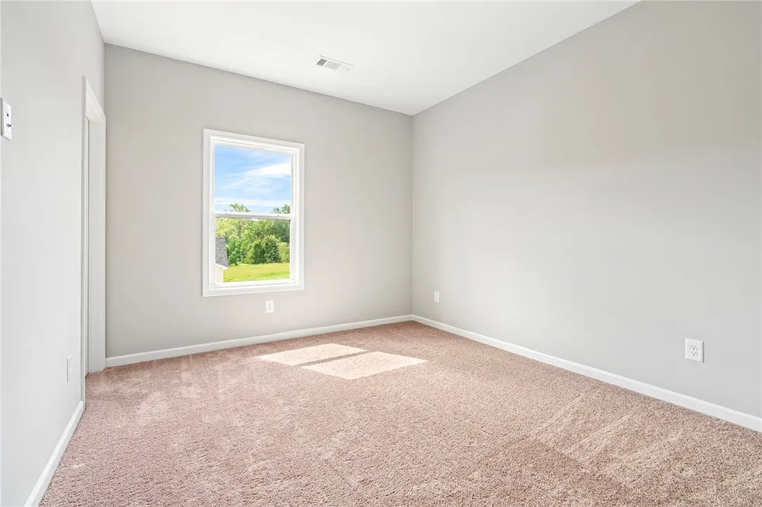 Plush carpeting and a picture window framing green views define this versatile bedroom.