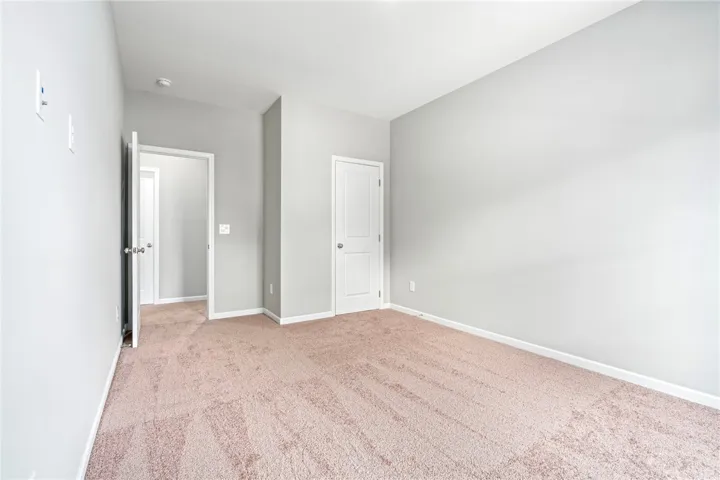 Plush wall-to-wall carpeting and clean neutral walls anchor this versatile secondary bedroom space.
