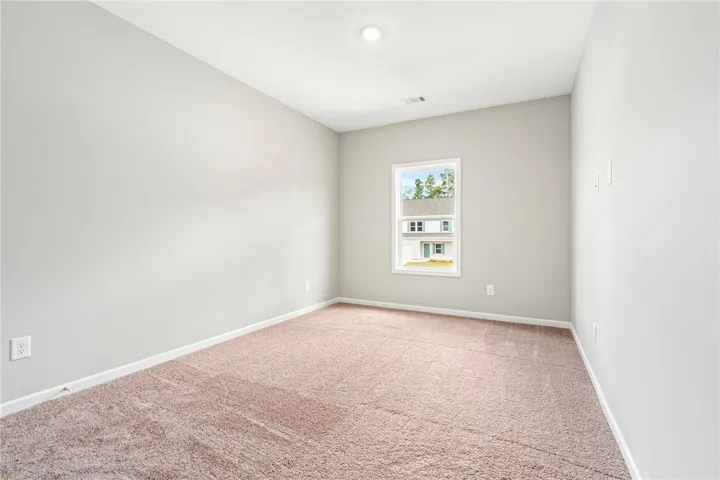 Soft carpeting underfoot and a single window define this versatile secondary bedroom space.