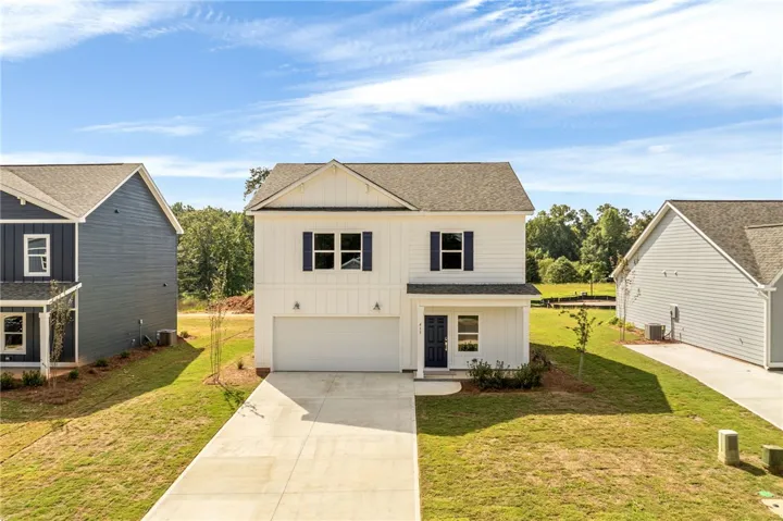 An inviting exterior displays crisp vertical siding and a neat concrete driveway leading to the garage.