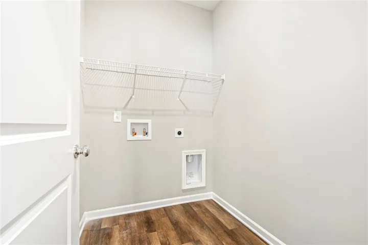 Rich wood-inspired flooring and utility hookups define this functional laundry space.