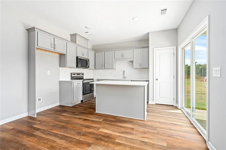 Rich wood floors anchor this modern cooking space, complete with sleek cabinetry and sliding glass doors.
