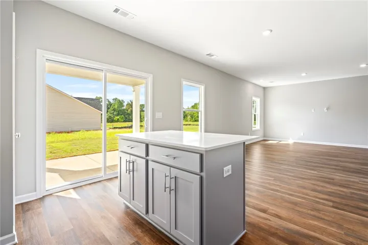 Warm wood-look flooring and a versatile kitchen island define this open, sunlit living area.