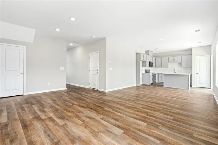 Rich wood-look flooring anchors a modern open layout flowing seamlessly into the kitchen.