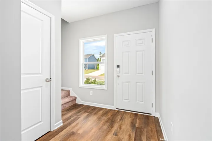 An inviting entrance foyer welcomes guests with durable wood-look flooring and clean white trim.