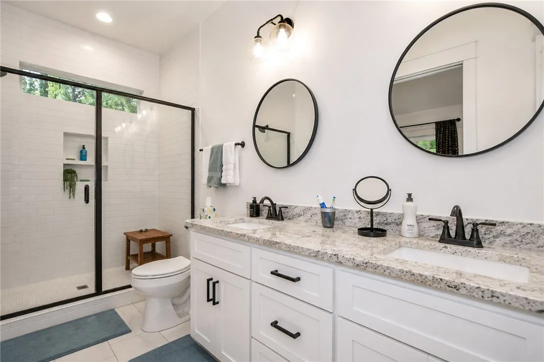 Luxurious bathroom offering a spacious shower, a dual vanity with granite counters, and recessed lighting.