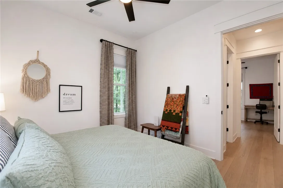 Well-lit sleeping quarters with bright white walls, hardwood flooring, and a large window overlooking natural surroundings.